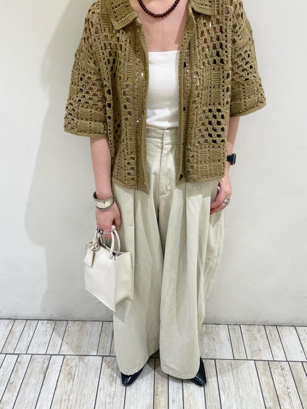 グリーン系のニット/セーター、ホワイト系のハンドバッグ、ブラウン系のネックレスを着用したレディースの春コーディネートの4枚目の写真