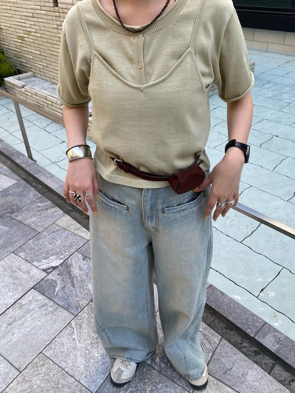 ブルー系のデニムパンツ、ベージュ系のカーディガン/ボレロ、ブラウン系のベルトを着用したレディースの春コーディネートの4枚目の写真