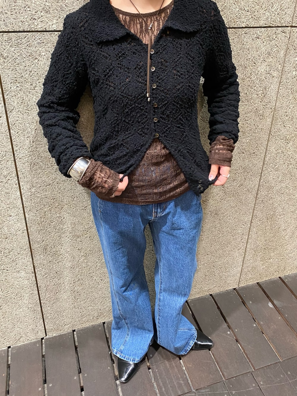 ブラック系のニット/セーター、ブラウン系のTシャツ/カットソー、ブルー系のデニムパンツを着用したレディースの冬コーディネートの4枚目の写真