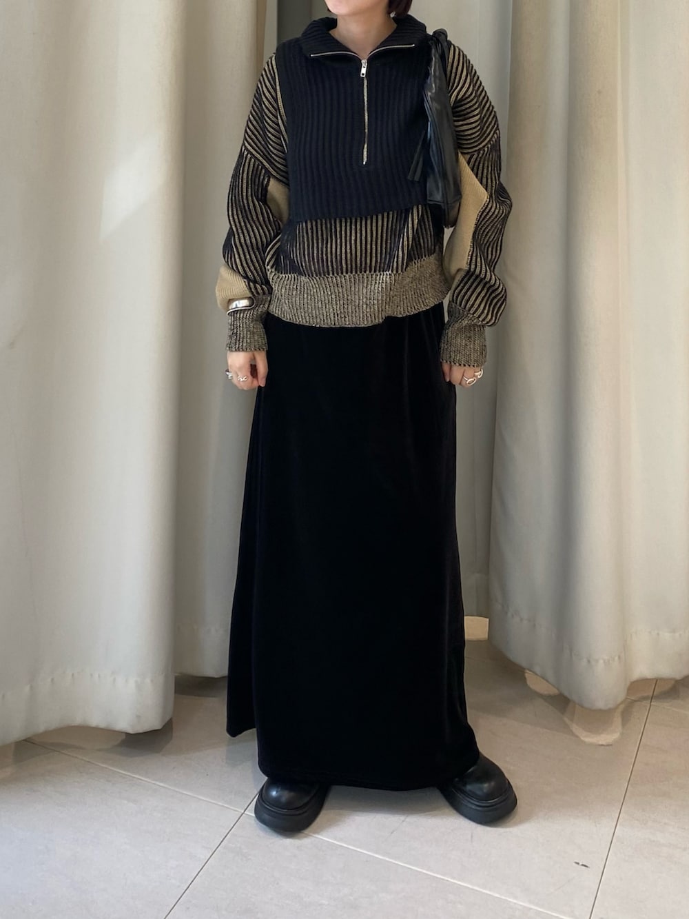 ブラック系のニット/セーター、ブラック系のスカート、ブラック系のハンドバッグを着用したレディースの秋コーディネートの2枚目の写真