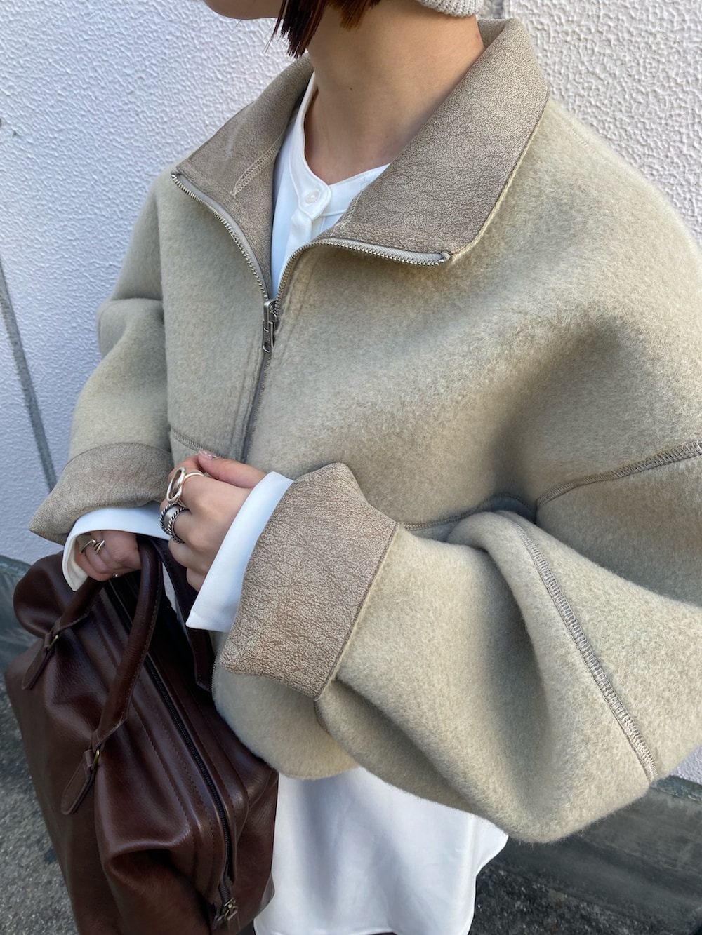 ベージュ系のその他アウター、ブラウン系のボストンバッグ、ホワイト系のワンピースを着用したレディースの秋コーディネートの6枚目の写真