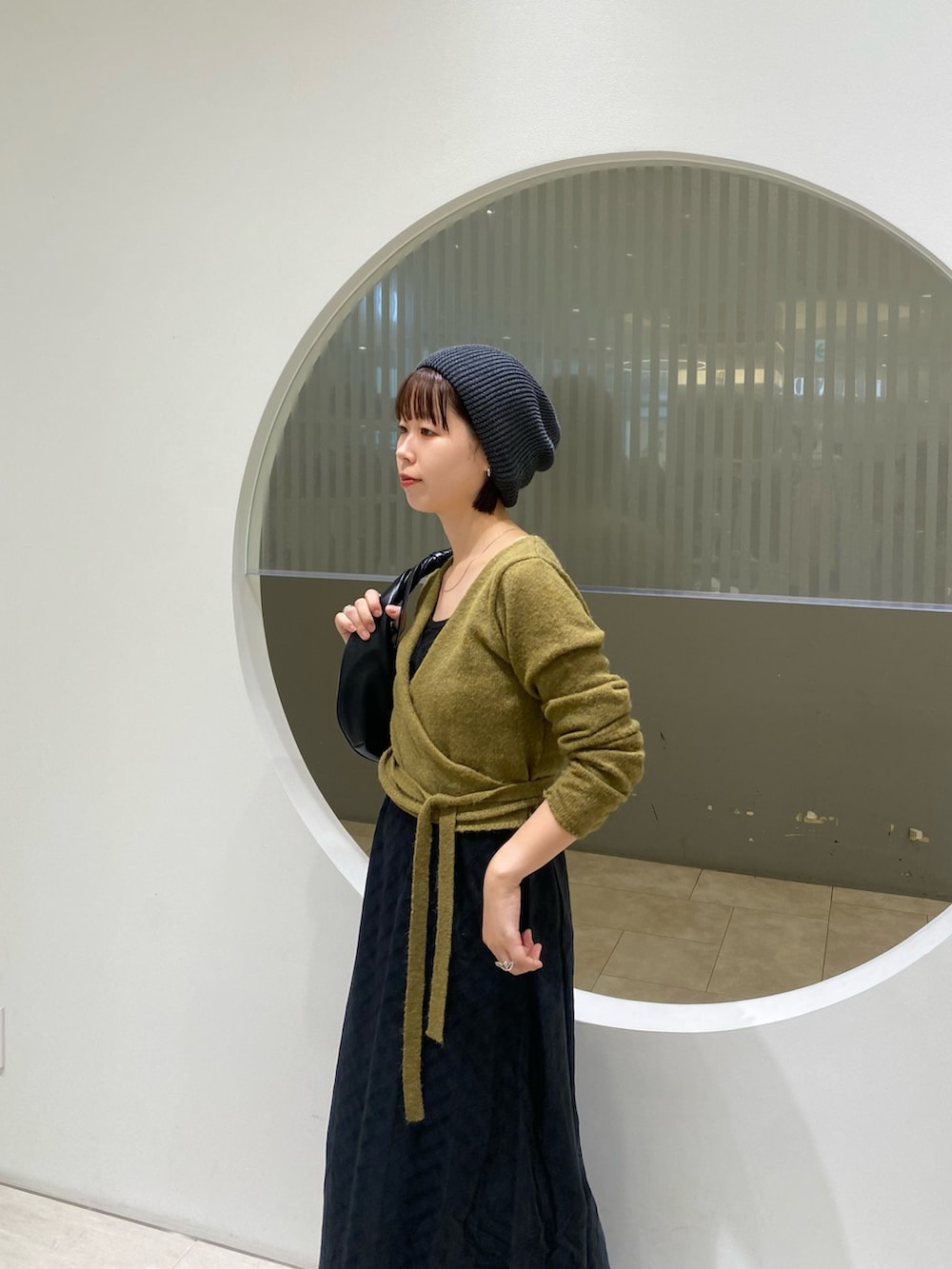 グリーン系のワンピース、ブラック系のブーツ、ブルー系のニット/セーターを着用したレディースの秋コーディネートの2枚目の写真