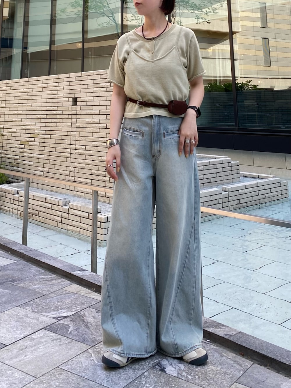 ブルー系のデニムパンツ、ベージュ系のカーディガン/ボレロ、ブラウン系のベルトを着用したレディースの春コーディネートの3枚目の写真