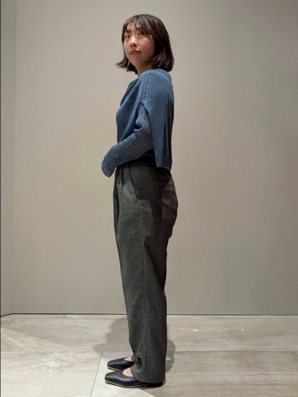 ブルー系のニット/セーター、グレー系のその他パンツ、ブラウン系のショルダーバッグを着用したレディースの秋コーディネートの3枚目の写真