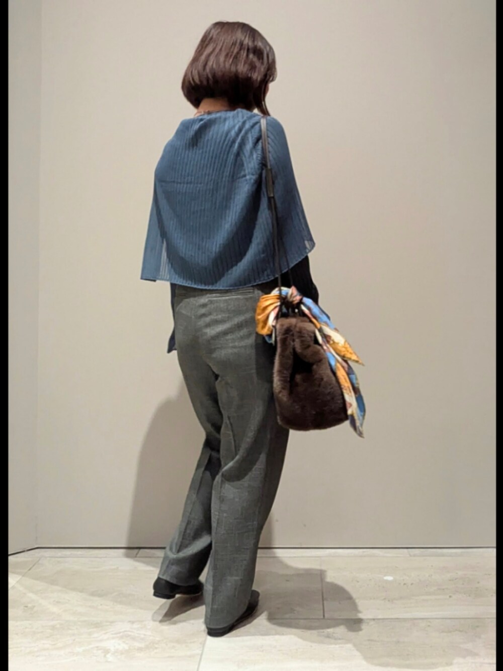 ブルー系のニット/セーター、グレー系のその他パンツ、ブラウン系のショルダーバッグを着用したレディースの秋コーディネートの2枚目の写真