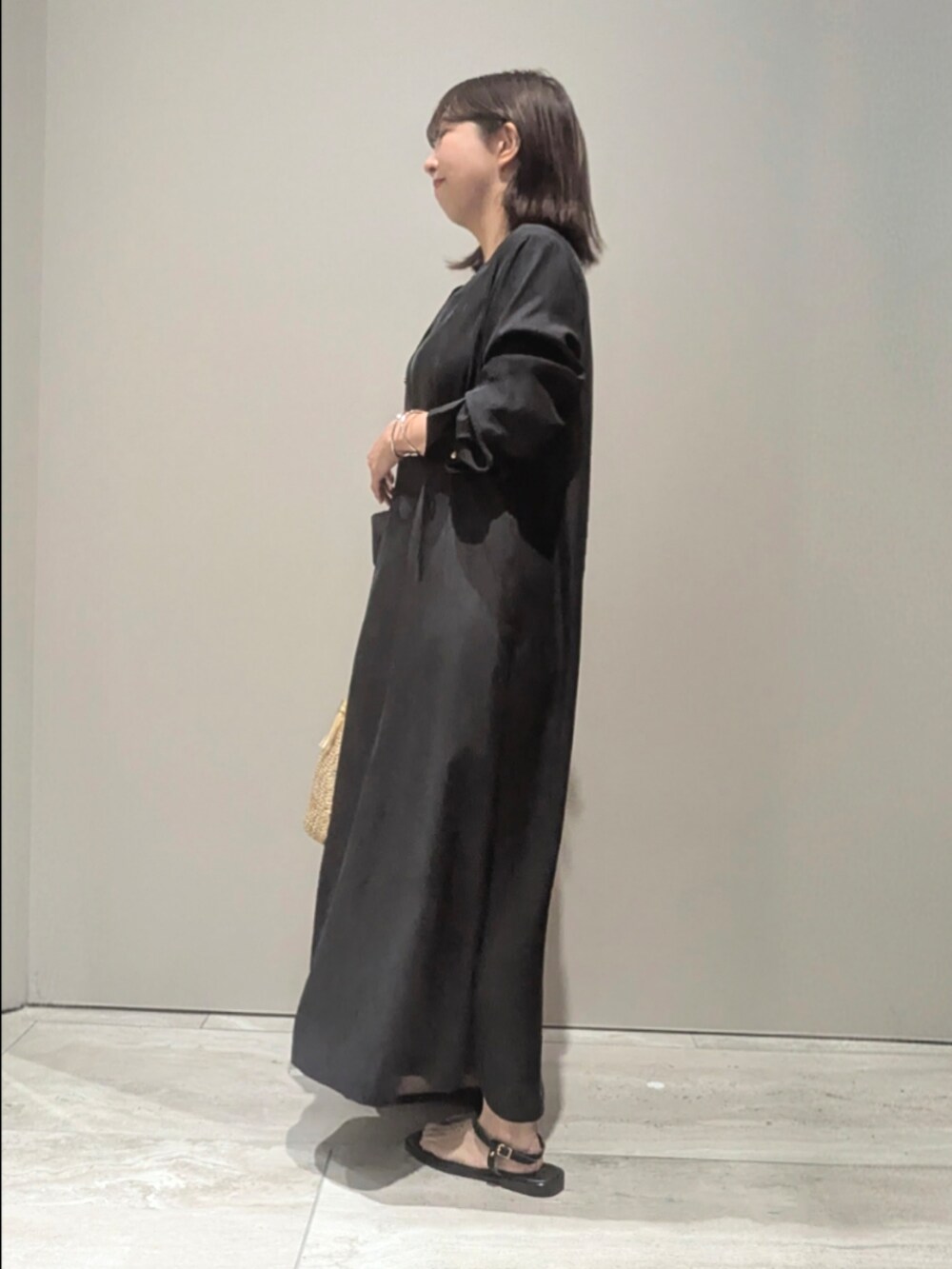 ブラック系のワンピース、ゴールド系のショルダーバッグ、シルバー系のバングル/リストバンドを着用したレディースの春コーディネートの4枚目の写真