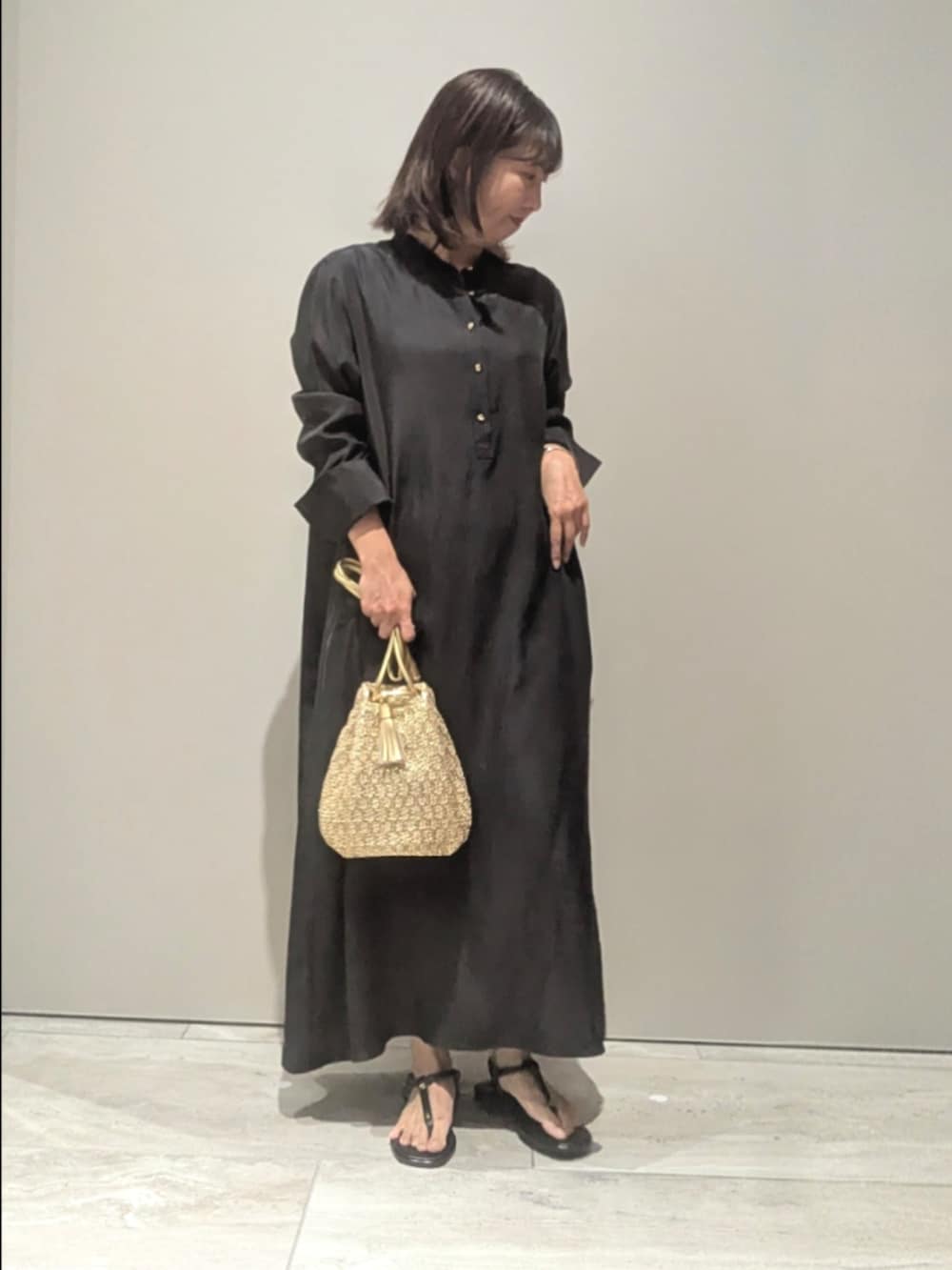 ブラック系のワンピース、ゴールド系のショルダーバッグ、シルバー系のバングル/リストバンドを着用したレディースの春コーディネートの6枚目の写真