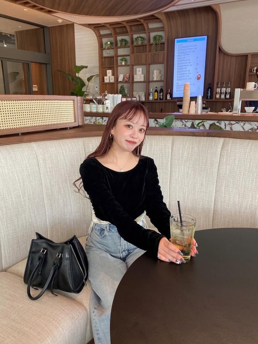 ブラウン系のブーツ、ブラック系のハンドバッグ、ブルー系のデニムパンツを着用したレディースの春コーディネートの2枚目の写真