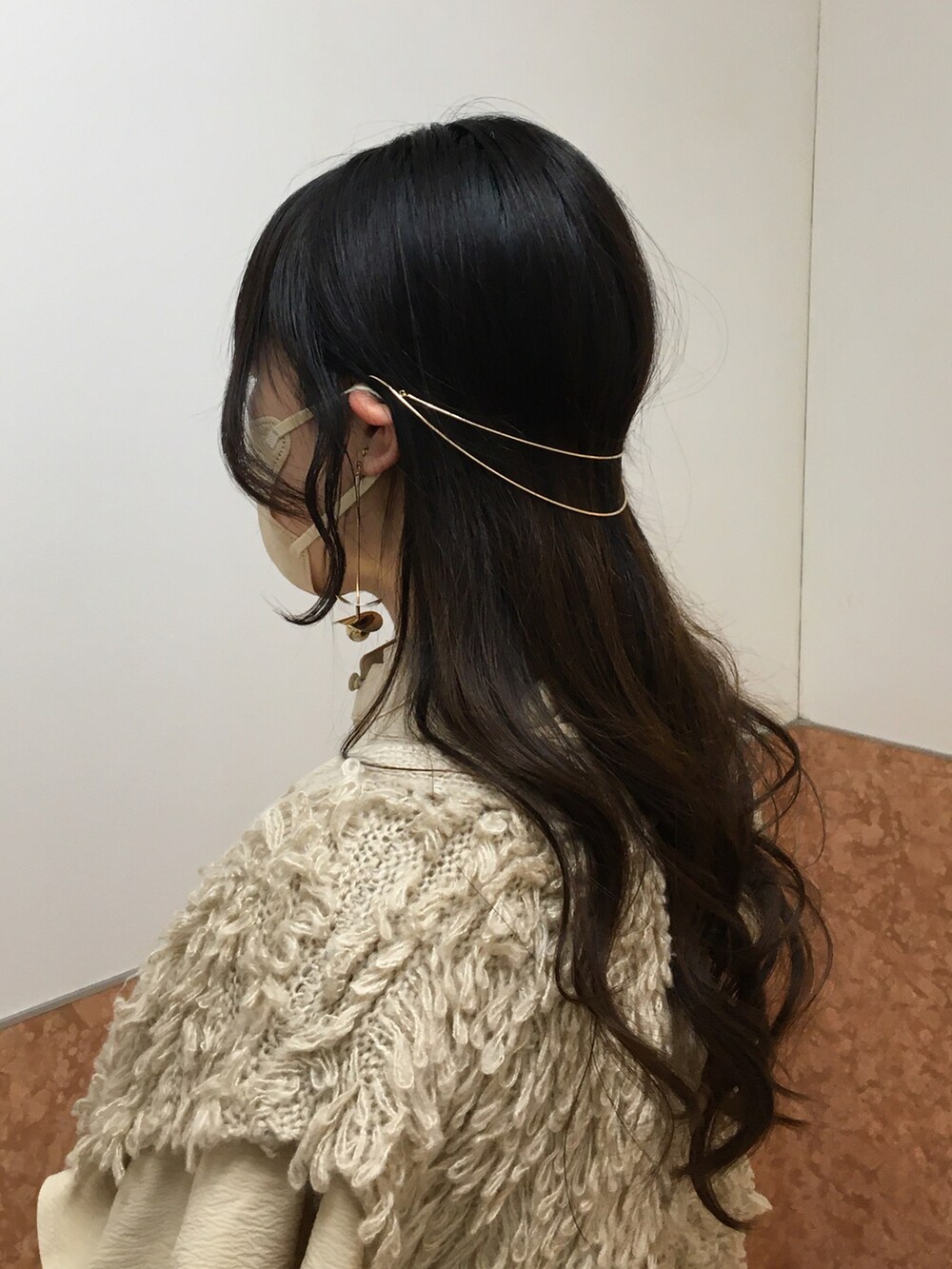 ホワイト系のハンドバッグ、ベージュ系のワンピース、ベージュ系のベストを着用したレディースの春コーディネートの4枚目の写真