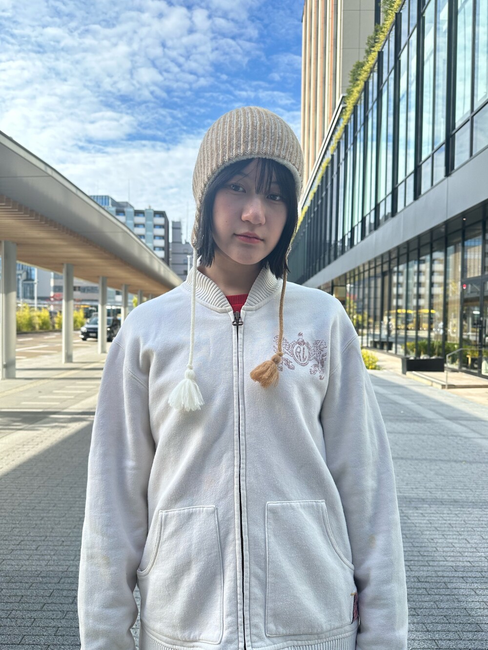 ホワイト系のパーカー、ブルー系のデニムパンツ、ブラック系のスニーカーを着用したレディースの秋コーディネートの2枚目の写真