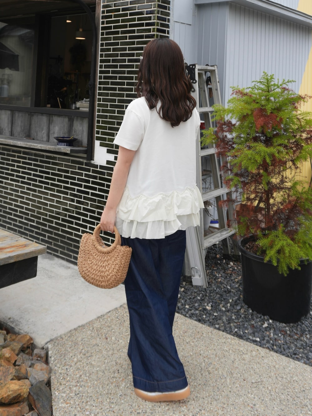 ブルー系のデニムパンツ、ホワイト系のTシャツ/カットソー、ベージュ系のかごバッグを着用したレディースの春コーディネートの2枚目の写真