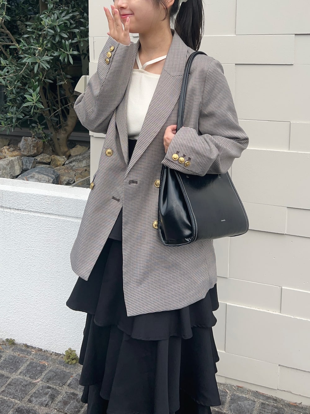 ブラウン系のテーラードジャケット、ブラウン系のパンプス、ホワイト系のニット/セーターを着用したレディースの秋コーディネートの2枚目の写真