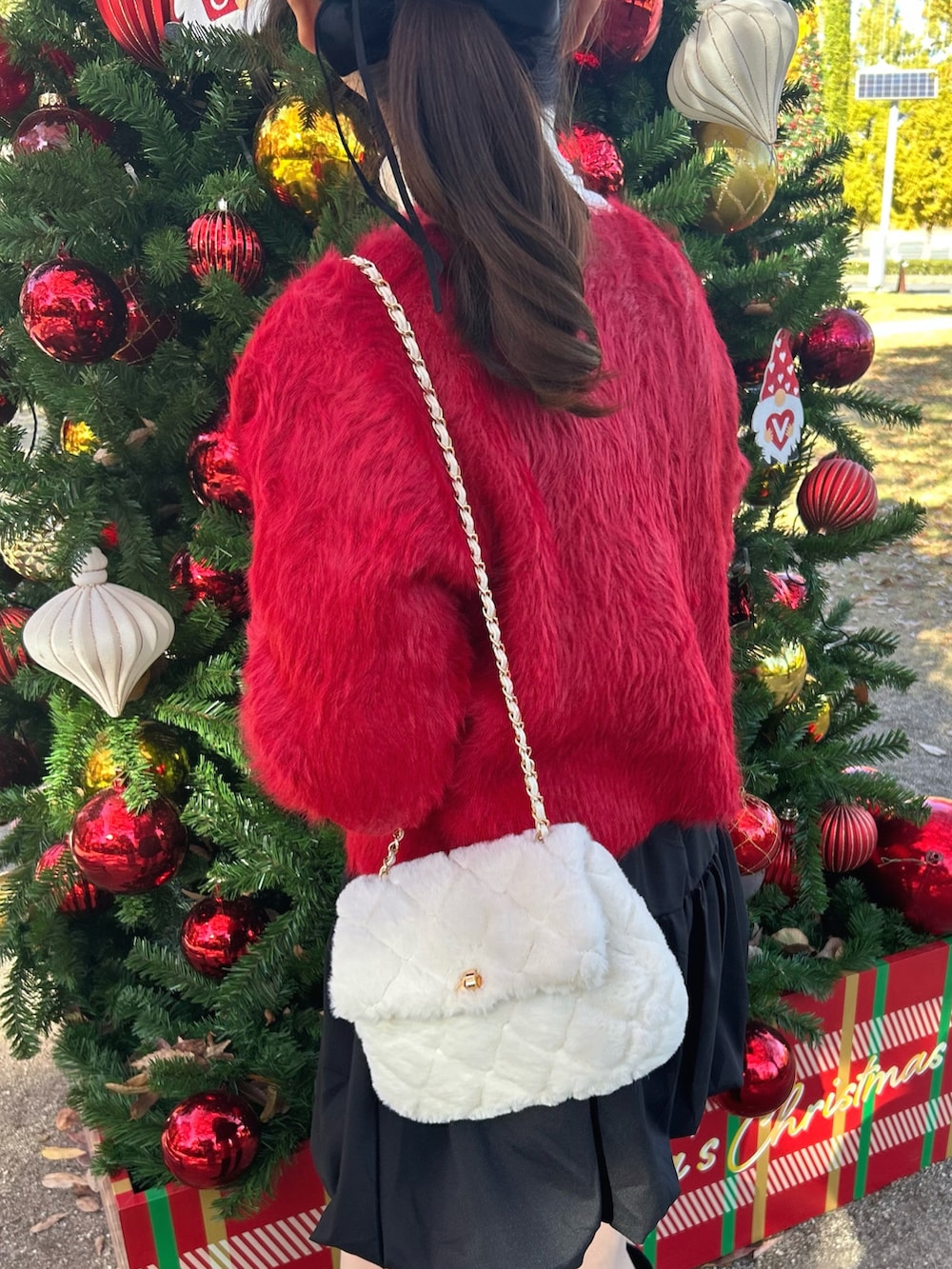 レッド系のカーディガン/ボレロ、ホワイト系のニット/セーター、ブラック系のスカートを着用したレディースの秋コーディネートの2枚目の写真