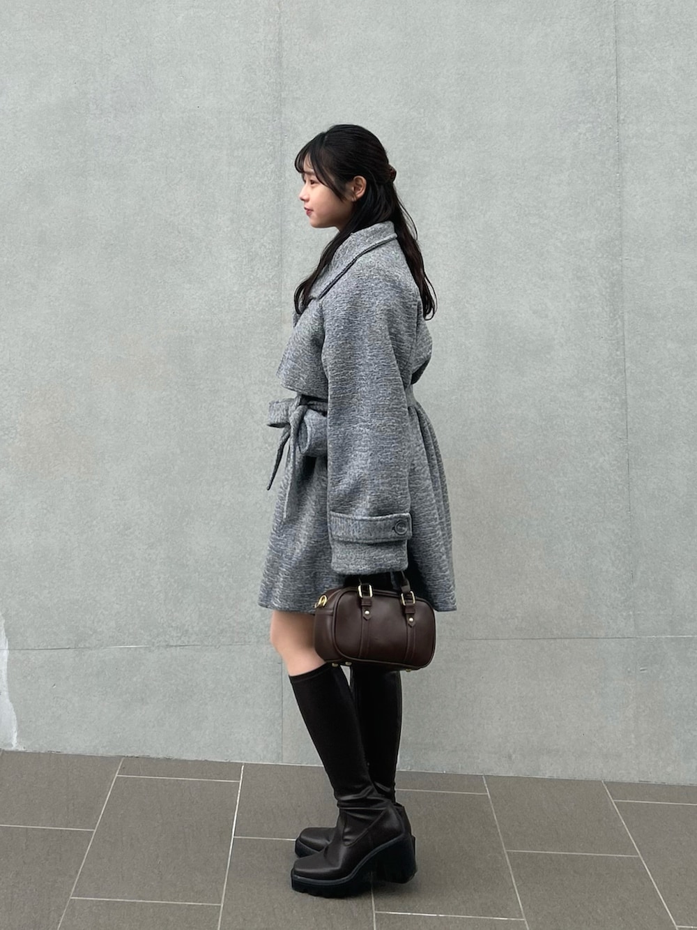 ホワイト系のニット/セーター、グレー系のステンカラーコート、ブラック系のスラックスを着用したレディースの冬コーディネートの2枚目の写真