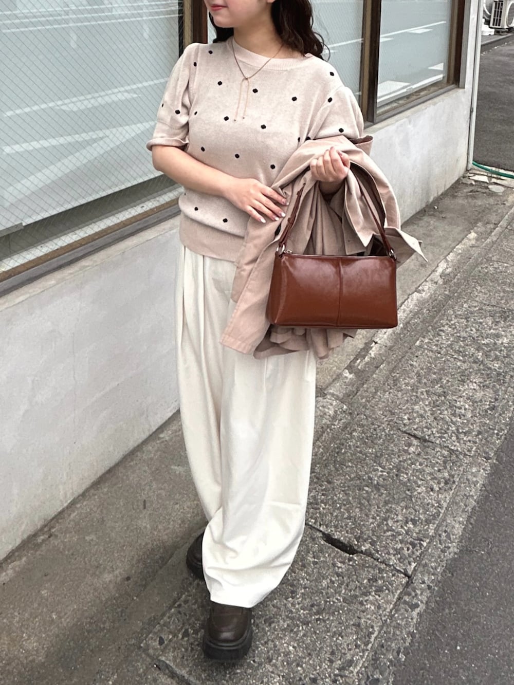 ベージュ系のトレンチコート、ベージュ系のニット/セーター、ホワイト系のスラックスを着用したレディースの春コーディネートの3枚目の写真