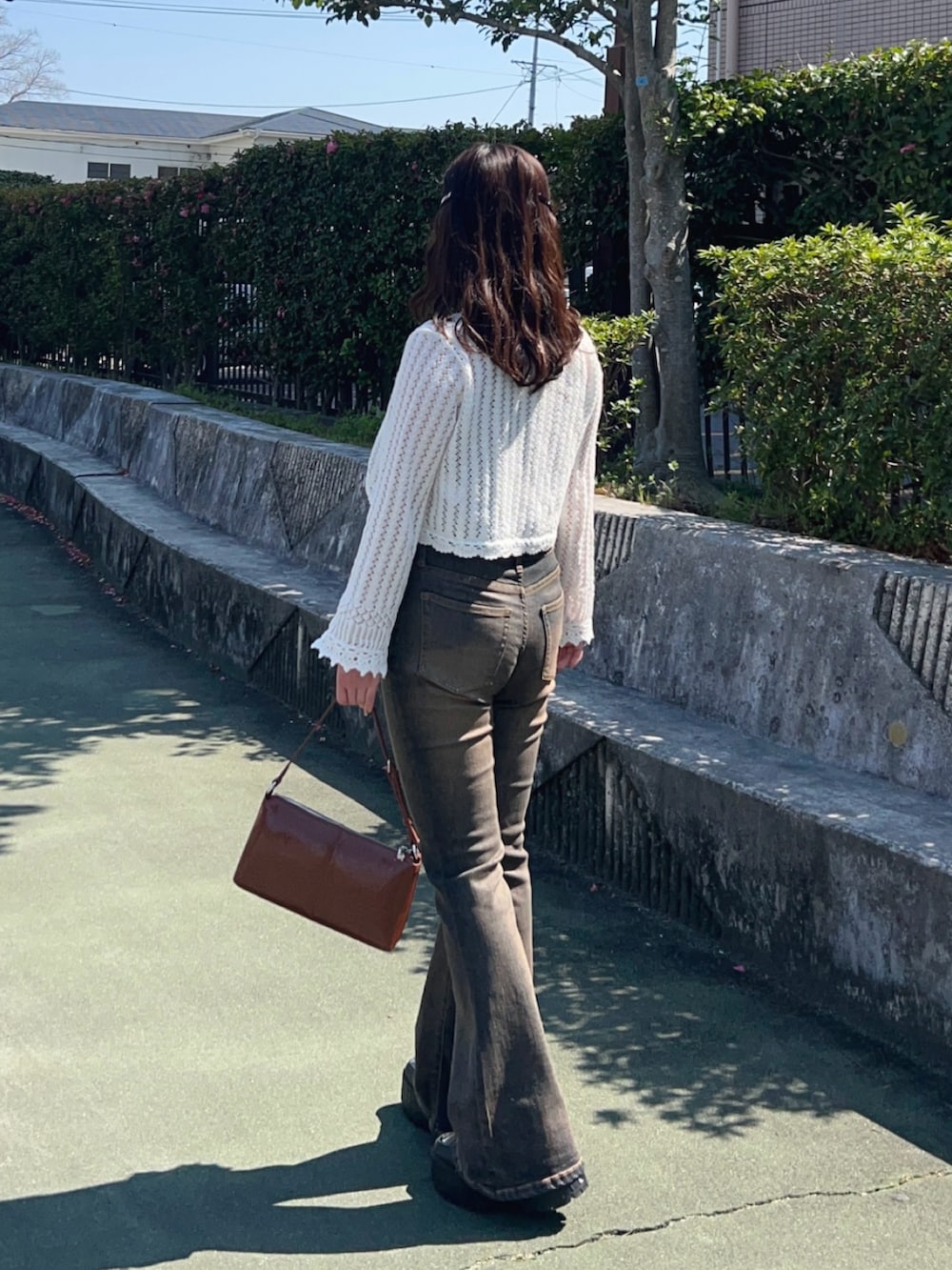 ブラック系のスニーカー、ブルー系のデニムパンツ、その他のショルダーバッグを着用したレディースの春コーディネートの2枚目の写真