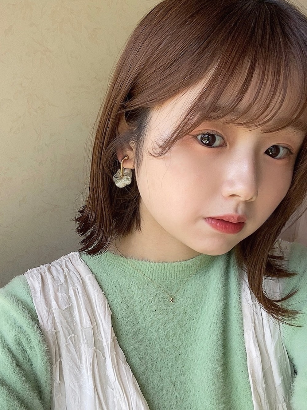 ホワイト系のワンピース、グリーン系のニット/セーター、ホワイト系のサンダルを着用したレディースの夏コーディネートの2枚目の写真