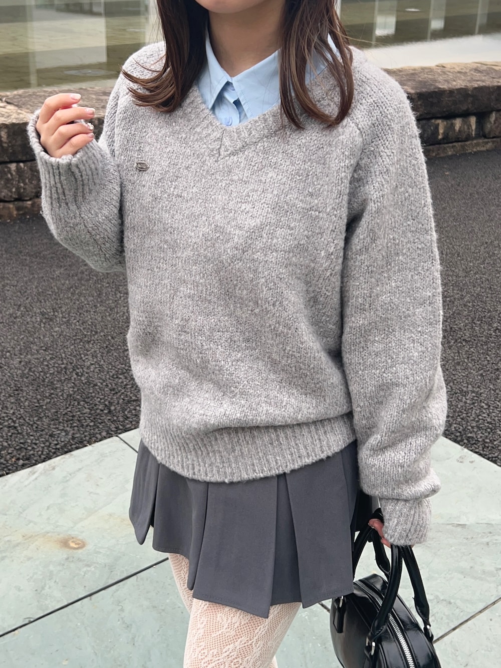 グレー系のニット/セーター、ブルー系のシャツ/ブラウス、グレー系のスカートを着用したレディースの冬コーディネートの2枚目の写真