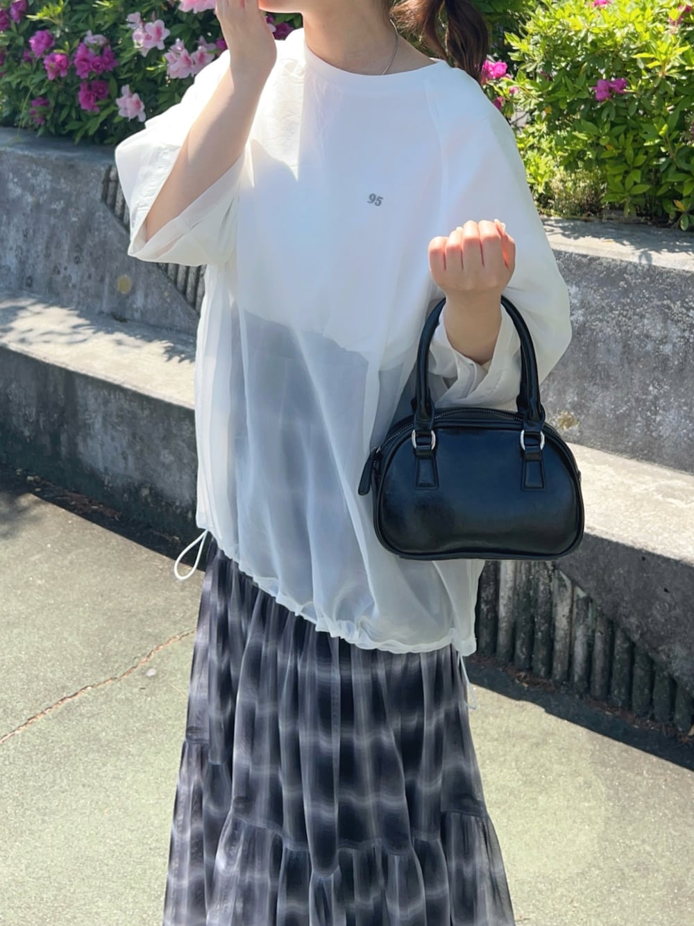 ブラック系のスカート、シルバー系のパンプス、ブラック系のハンドバッグを着用したレディースの春コーディネートの2枚目の写真