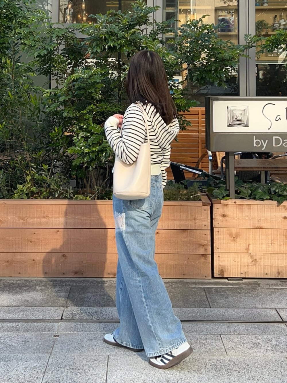 ホワイト系のパーカー、ブルー系のデニムパンツ、ブルー系のスニーカーを着用したレディースの冬コーディネートの2枚目の写真