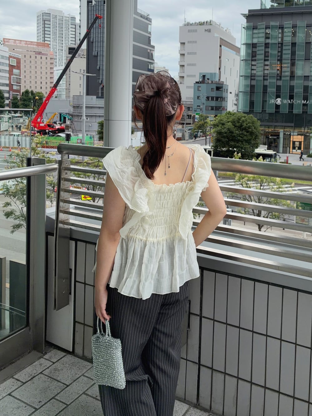 ホワイト系のシャツ/ブラウス、グレー系のスラックス、ホワイト系のスニーカーを着用したレディースの夏コーディネートの4枚目の写真