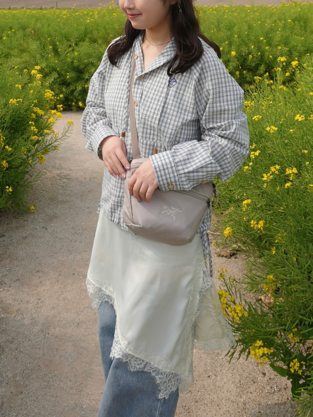 ベージュ系のブルゾン、ブルー系のデニムパンツ、ホワイト系のワンピースを着用したレディースの春コーディネートの5枚目の写真