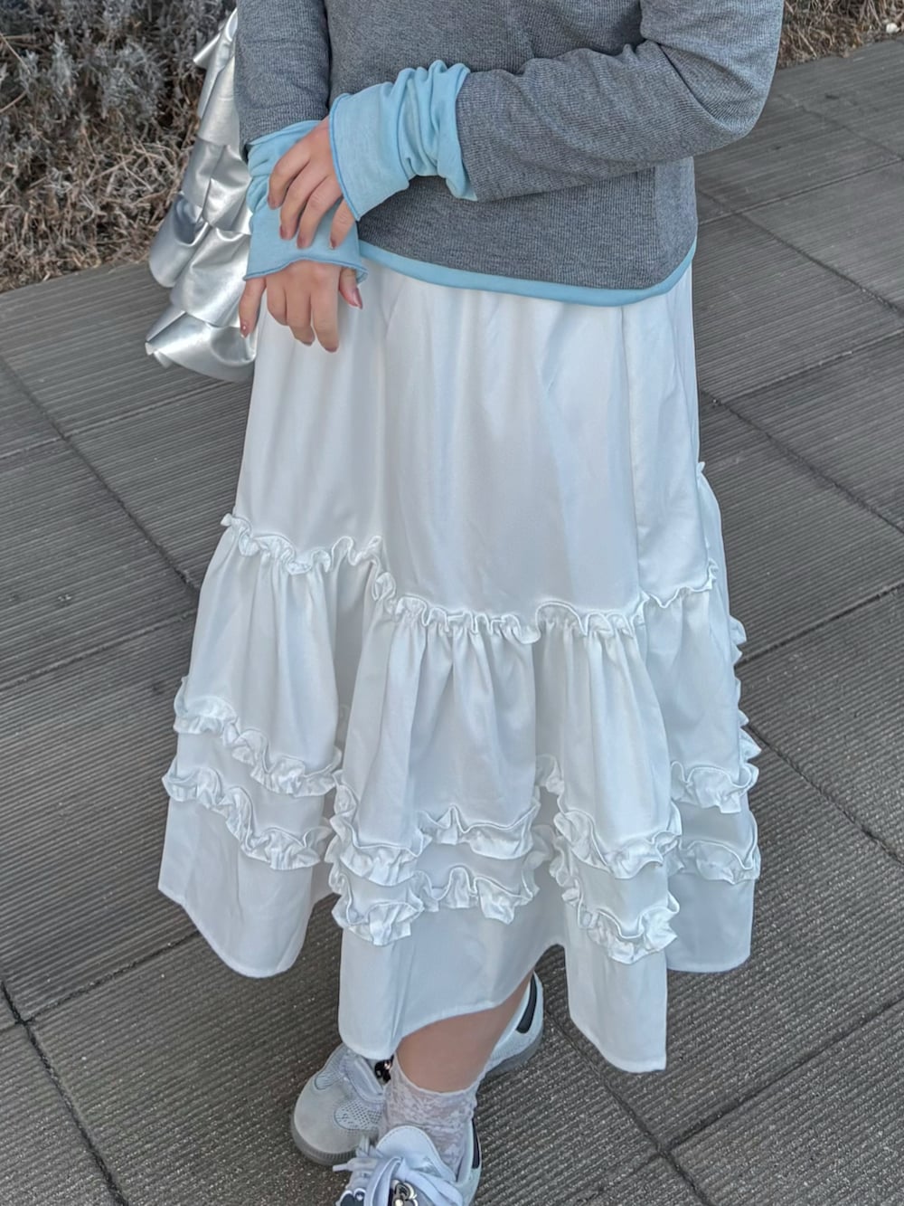 グレー系のTシャツ/カットソー、ホワイト系のスカート、ホワイト系のスニーカーを着用したレディースの春コーディネートの4枚目の写真