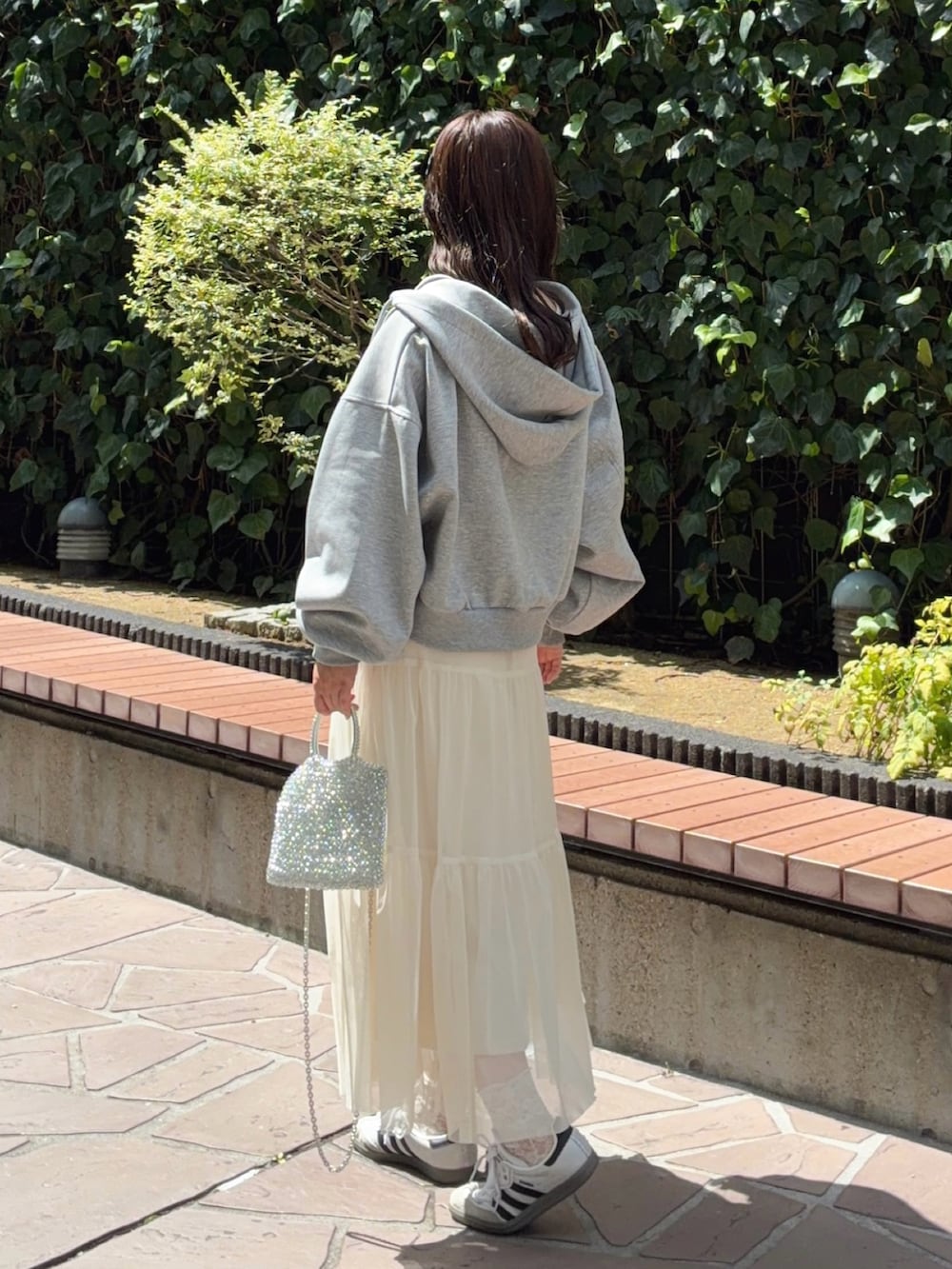 グレー系のパーカー、ホワイト系のスカート、ホワイト系のTシャツ/カットソーを着用したレディースの秋コーディネートの3枚目の写真