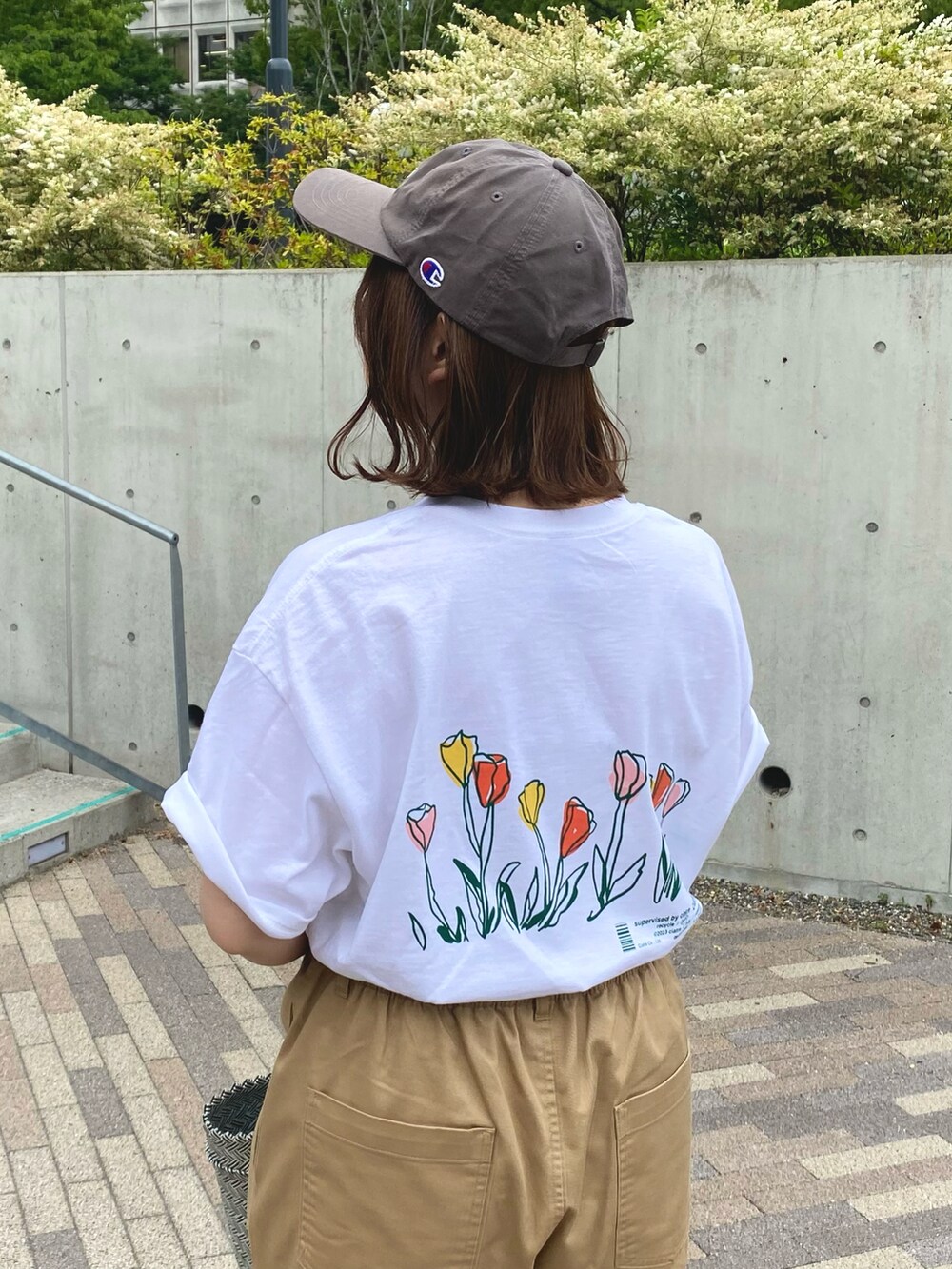 ブラック系のかごバッグ、ベージュ系のチノパンツ、ホワイト系のTシャツ/カットソーを着用したレディースの夏コーディネートの2枚目の写真