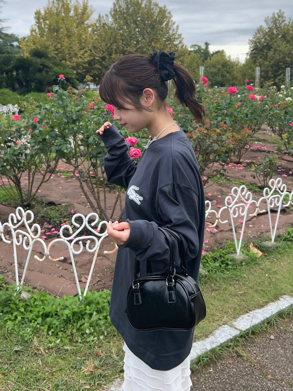 グレー系のTシャツ/カットソー、ホワイト系のスカート、ブラック系のブーツを着用したレディースの秋コーディネートの4枚目の写真