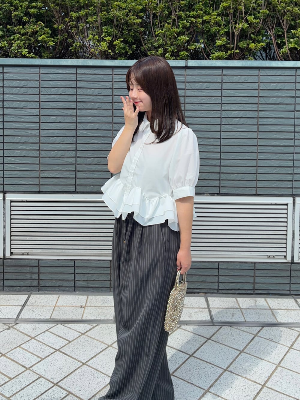 ホワイト系のシャツ/ブラウス、ホワイト系のパンプス、グレー系のスラックスを着用したレディースの夏コーディネートの4枚目の写真