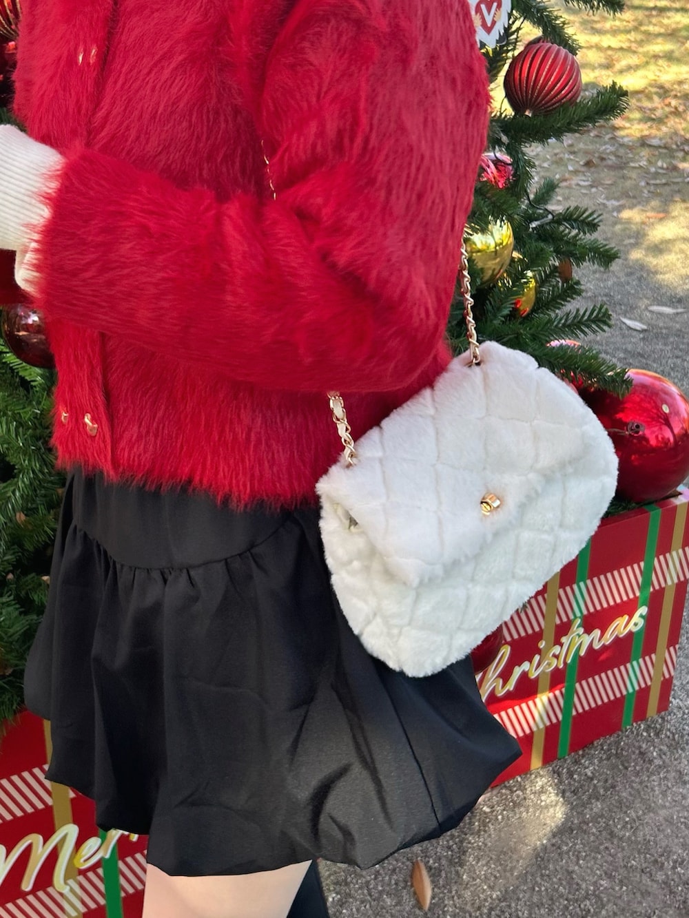 レッド系のカーディガン/ボレロ、ホワイト系のニット/セーター、ブラック系のスカートを着用したレディースの秋コーディネートの4枚目の写真