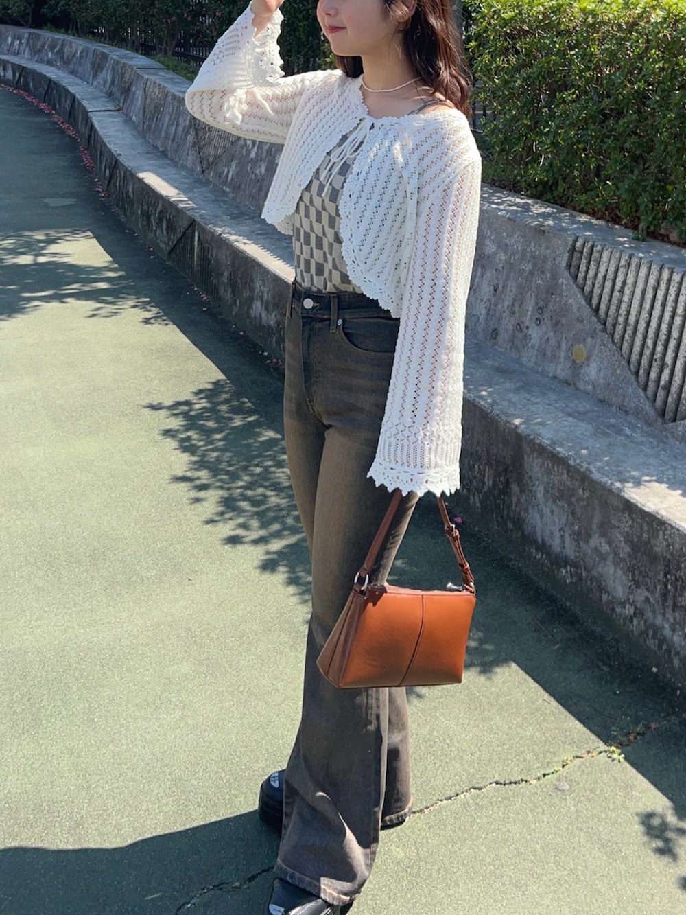 ブラック系のスニーカー、ブルー系のデニムパンツ、その他のショルダーバッグを着用したレディースの春コーディネートの4枚目の写真