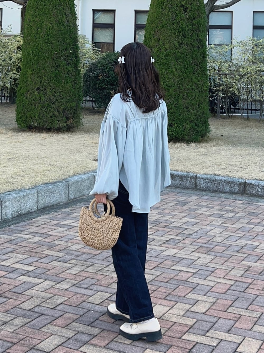 ホワイト系のローファー、ブルー系のシャツ/ブラウス、ベージュ系のかごバッグを着用したレディースの春コーディネートの2枚目の写真