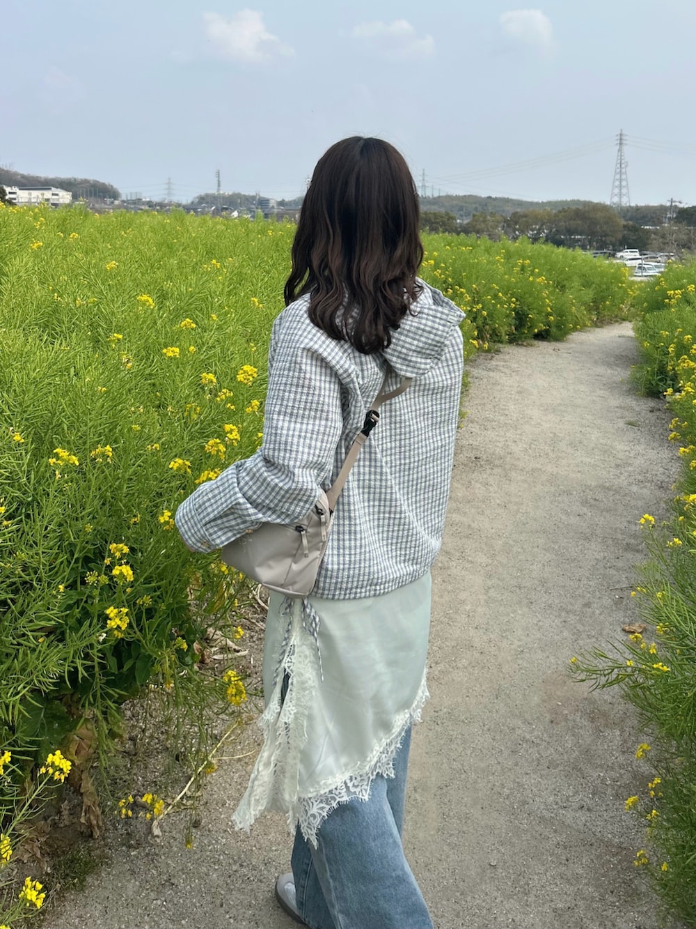 ベージュ系のブルゾン、ブルー系のデニムパンツ、ホワイト系のワンピースを着用したレディースの春コーディネートの4枚目の写真