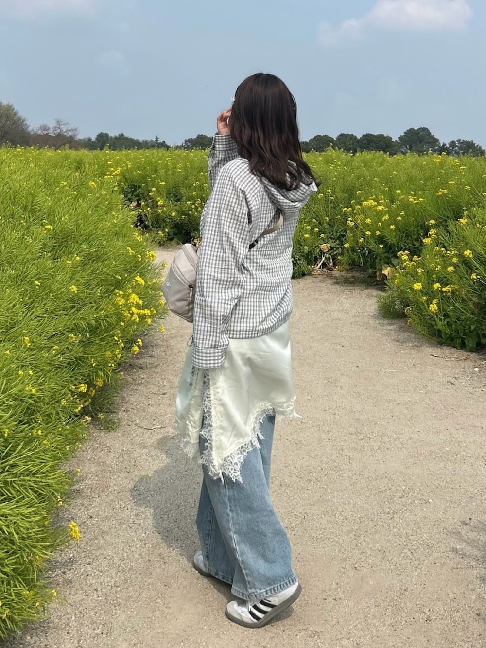 ベージュ系のブルゾン、ブルー系のデニムパンツ、ホワイト系のワンピースを着用したレディースの春コーディネートの2枚目の写真