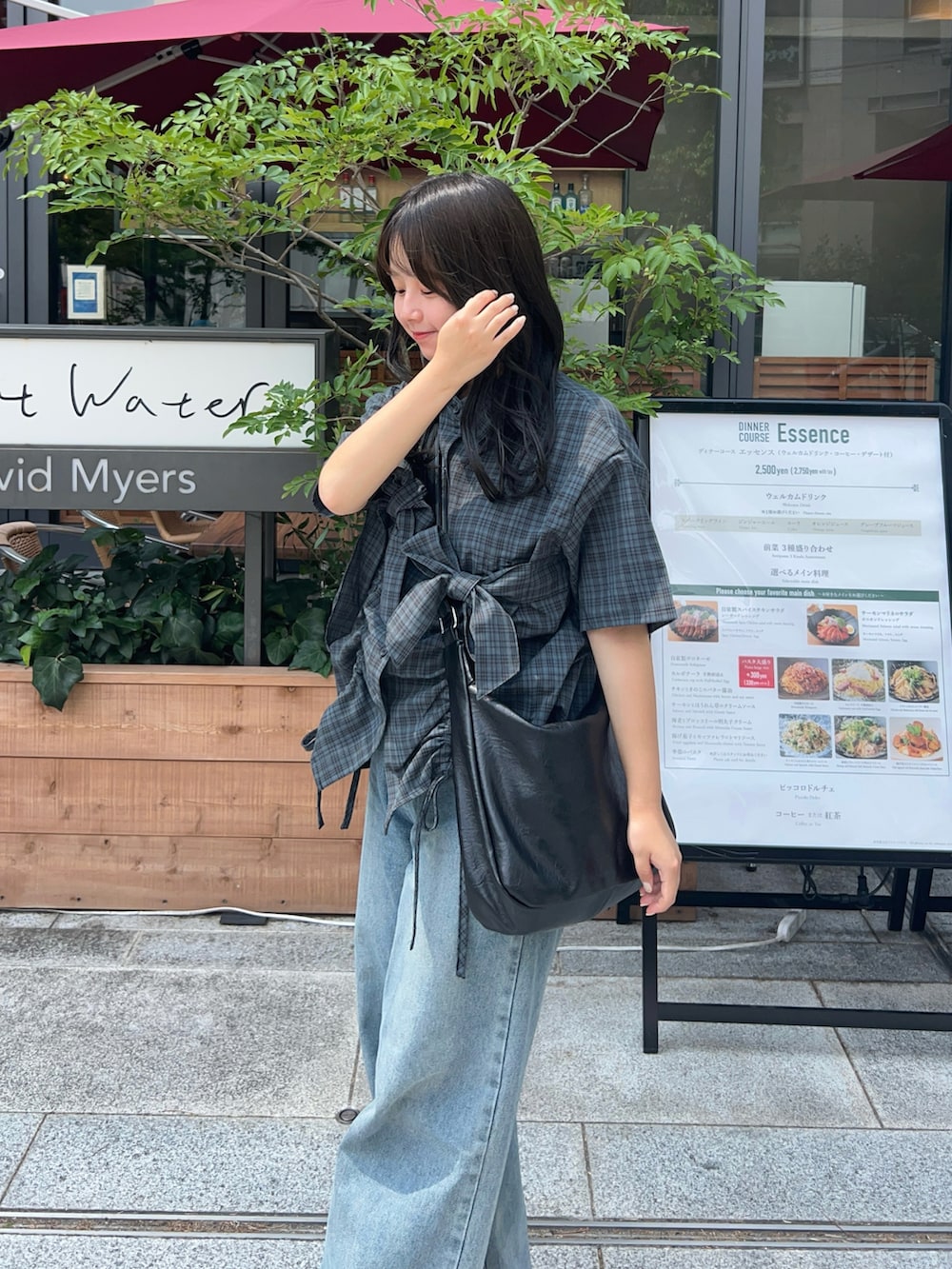 ブルー系のデニムパンツ、ブラック系のショルダーバッグ、グレー系のシャツ/ブラウスを着用したレディースの夏コーディネートの2枚目の写真