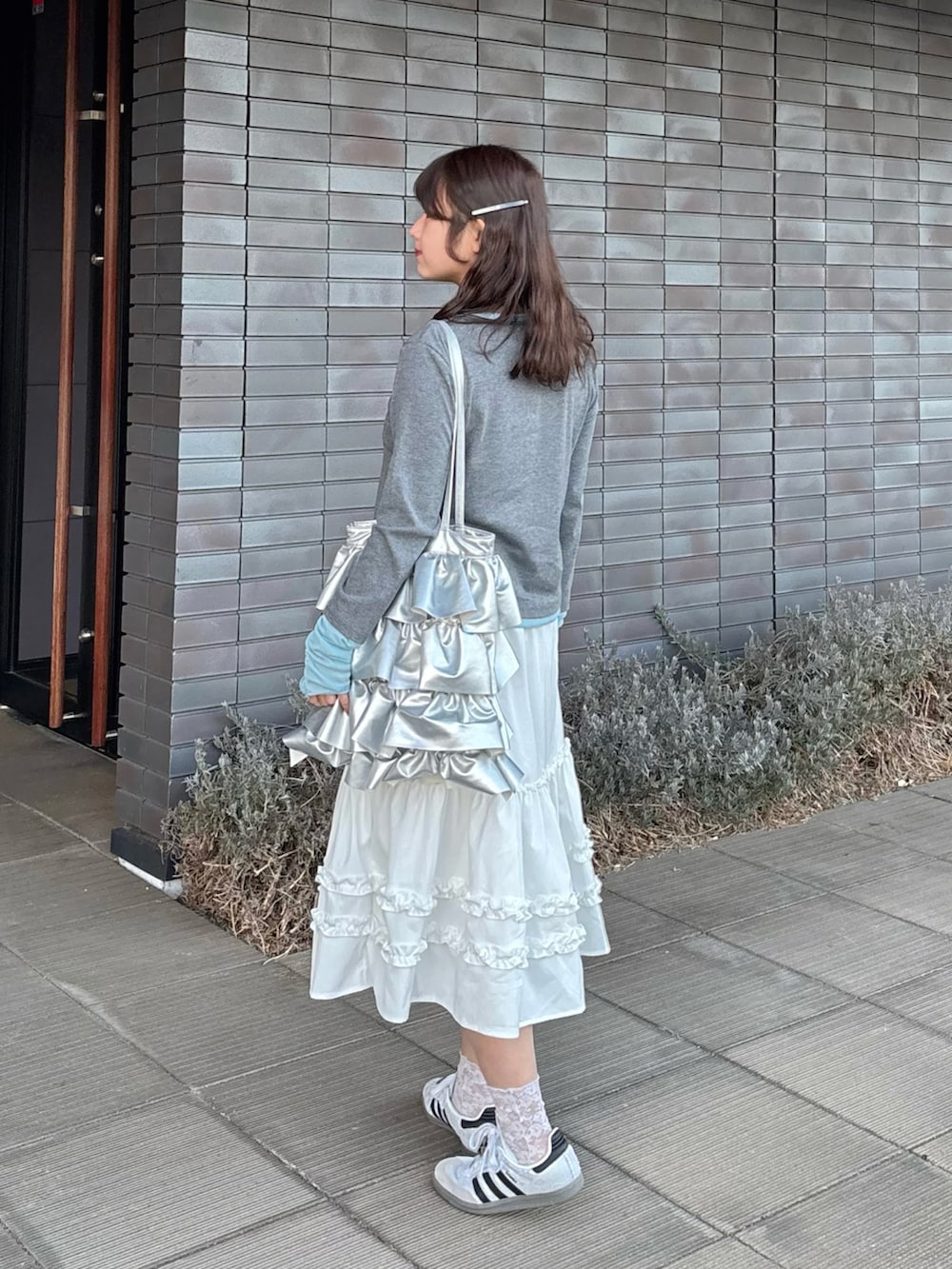 グレー系のTシャツ/カットソー、ホワイト系のスカート、ホワイト系のスニーカーを着用したレディースの春コーディネートの2枚目の写真
