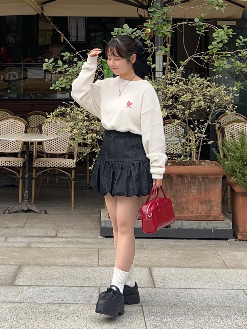 その他のTシャツ/カットソー、ブラック系のスカート、レッド系のボストンバッグを着用したレディースの秋コーディネートの3枚目の写真