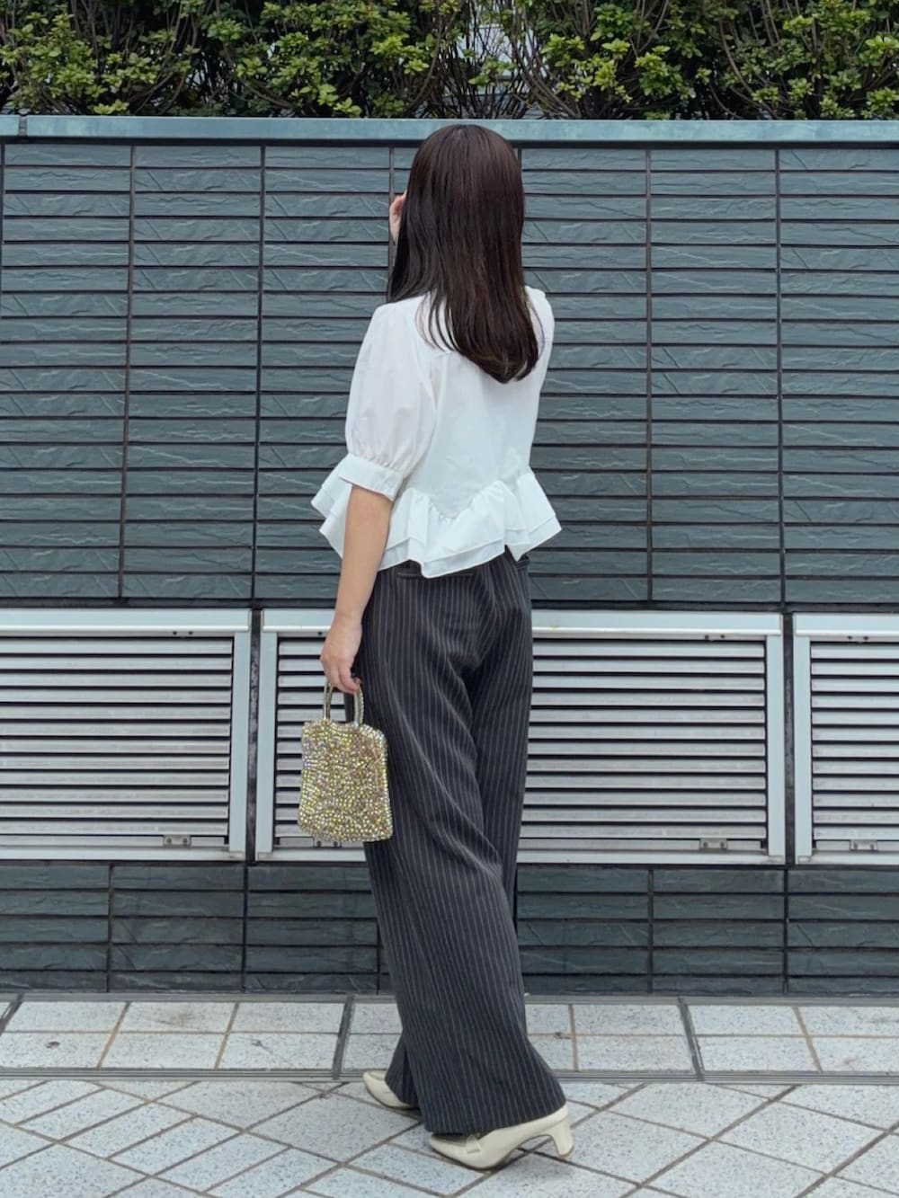 ホワイト系のシャツ/ブラウス、ホワイト系のパンプス、グレー系のスラックスを着用したレディースの夏コーディネートの3枚目の写真