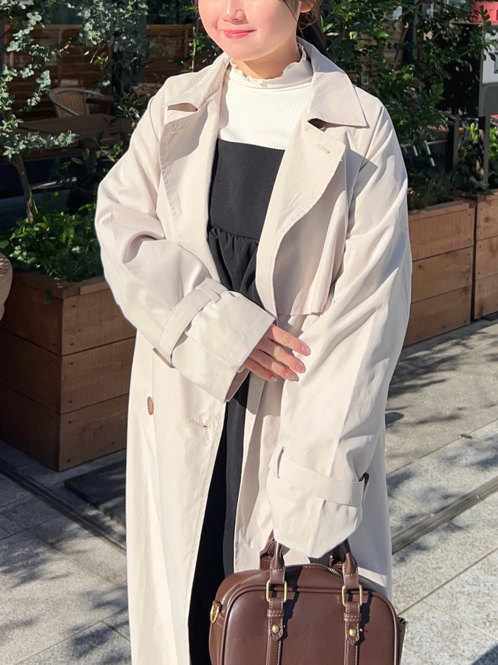 ホワイト系のトレンチコート、ブラック系のワンピース、ホワイト系のTシャツ/カットソーを着用したレディースの春コーディネートの3枚目の写真