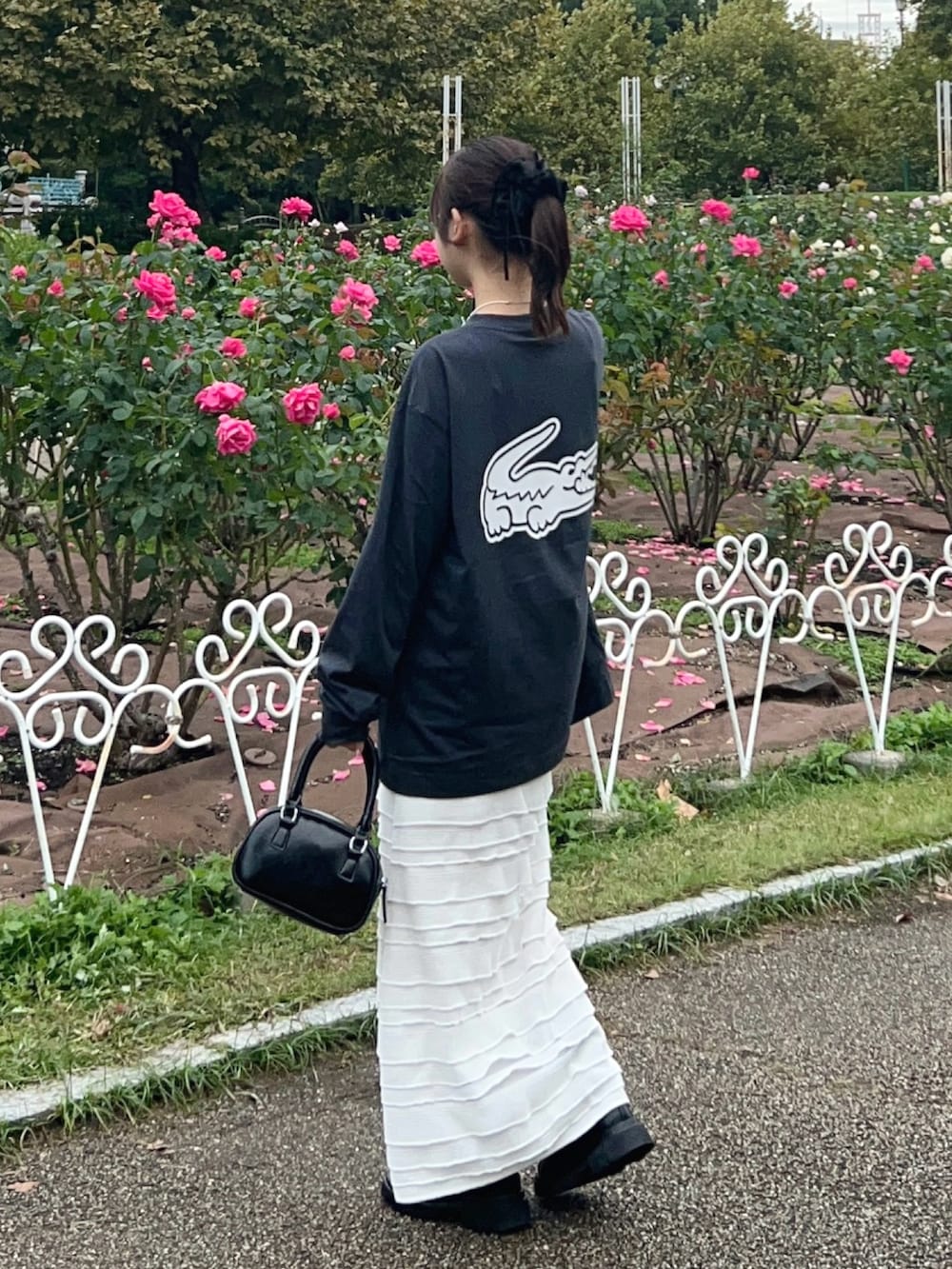 グレー系のTシャツ/カットソー、ホワイト系のスカート、ブラック系のブーツを着用したレディースの秋コーディネートの3枚目の写真