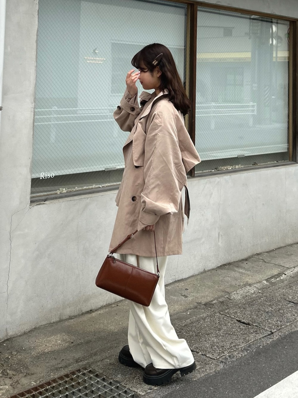 ベージュ系のトレンチコート、ベージュ系のニット/セーター、ホワイト系のスラックスを着用したレディースの春コーディネートの2枚目の写真
