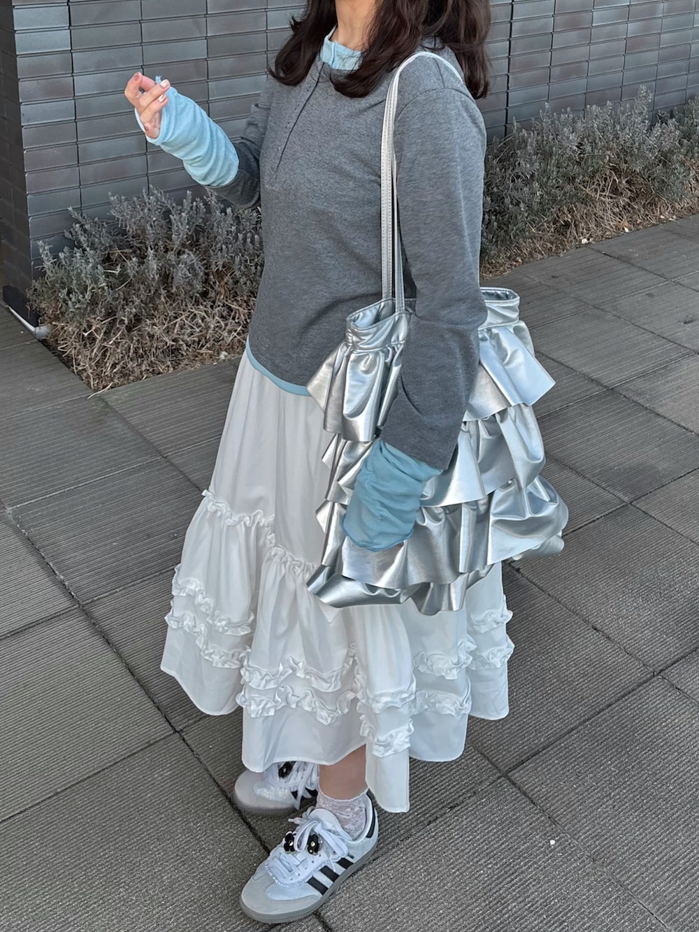 グレー系のTシャツ/カットソー、ホワイト系のスカート、ホワイト系のスニーカーを着用したレディースの春コーディネートの3枚目の写真