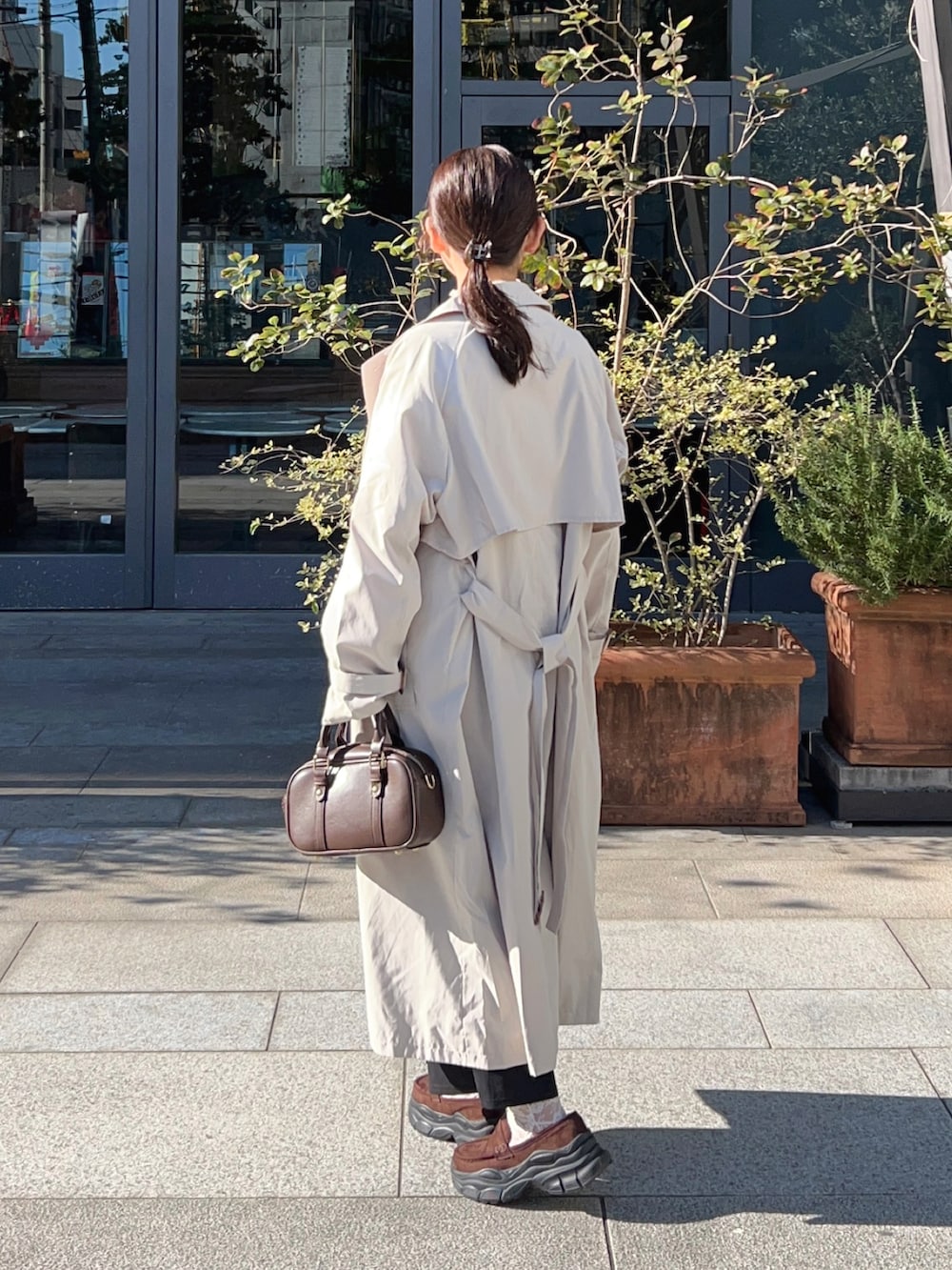 ホワイト系のトレンチコート、ブラック系のワンピース、ホワイト系のTシャツ/カットソーを着用したレディースの春コーディネートの2枚目の写真