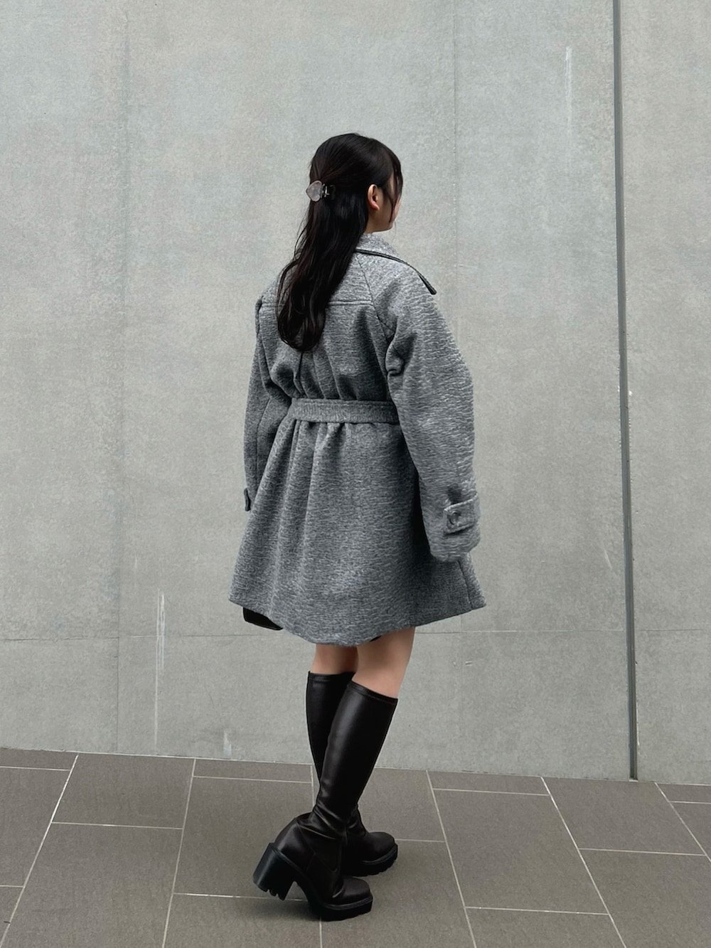 ホワイト系のニット/セーター、グレー系のステンカラーコート、ブラック系のスラックスを着用したレディースの冬コーディネートの5枚目の写真