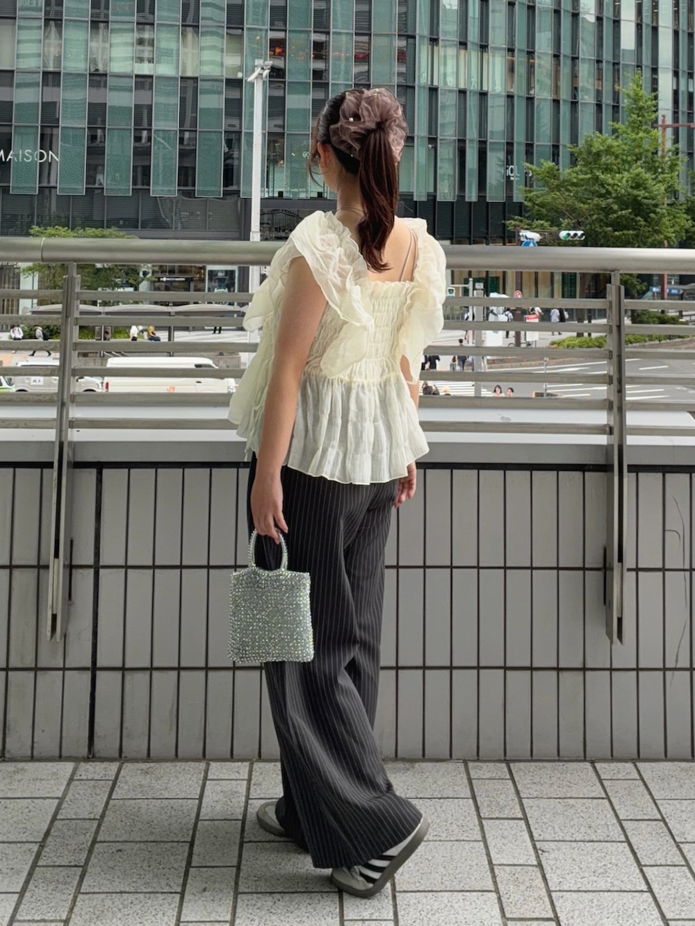 ホワイト系のシャツ/ブラウス、グレー系のスラックス、ホワイト系のスニーカーを着用したレディースの夏コーディネートの2枚目の写真