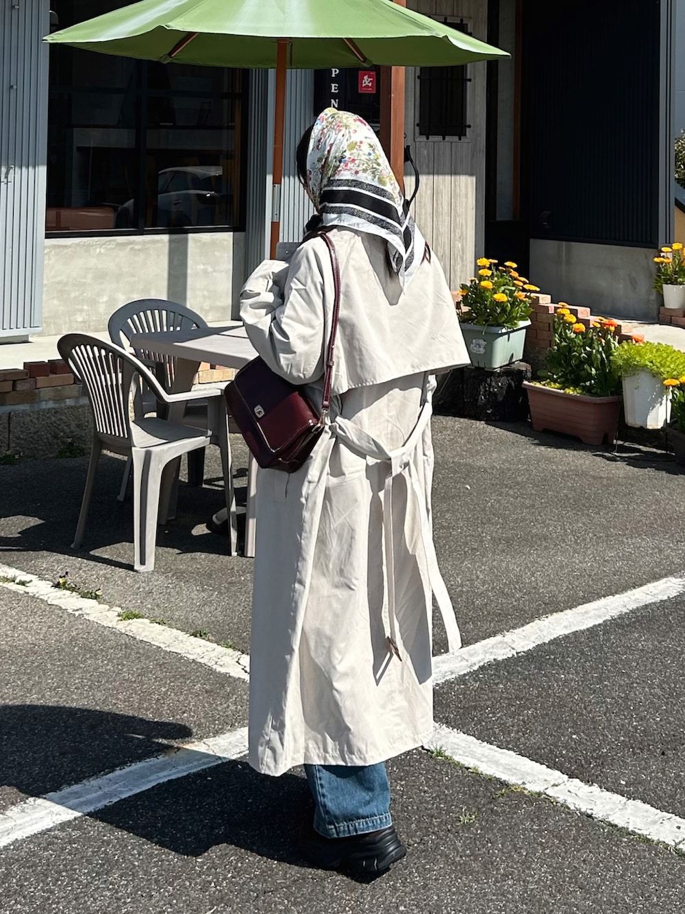 グレー系のカーディガン/ボレロ、ホワイト系のトレンチコート、レッド系のショルダーバッグを着用したレディースの春コーディネートの2枚目の写真