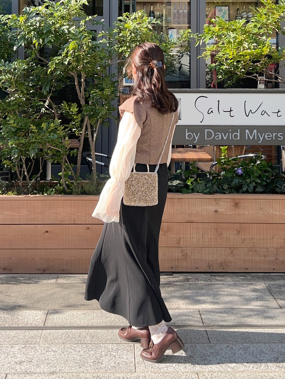 ブラック系のスカート、ブラウン系のノーカラージャケット、ホワイト系のTシャツ/カットソーを着用したレディースの春コーディネートの2枚目の写真