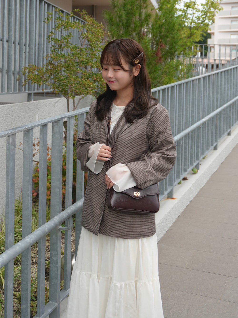ホワイト系のスカート、ブラウン系のローファー、ホワイト系のTシャツ/カットソーを着用したレディースの夏コーディネートの2枚目の写真